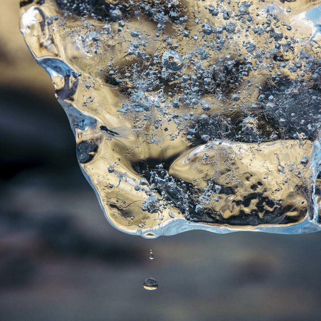 A shard of glacier ice full of trapped air bubbles, melting in the light